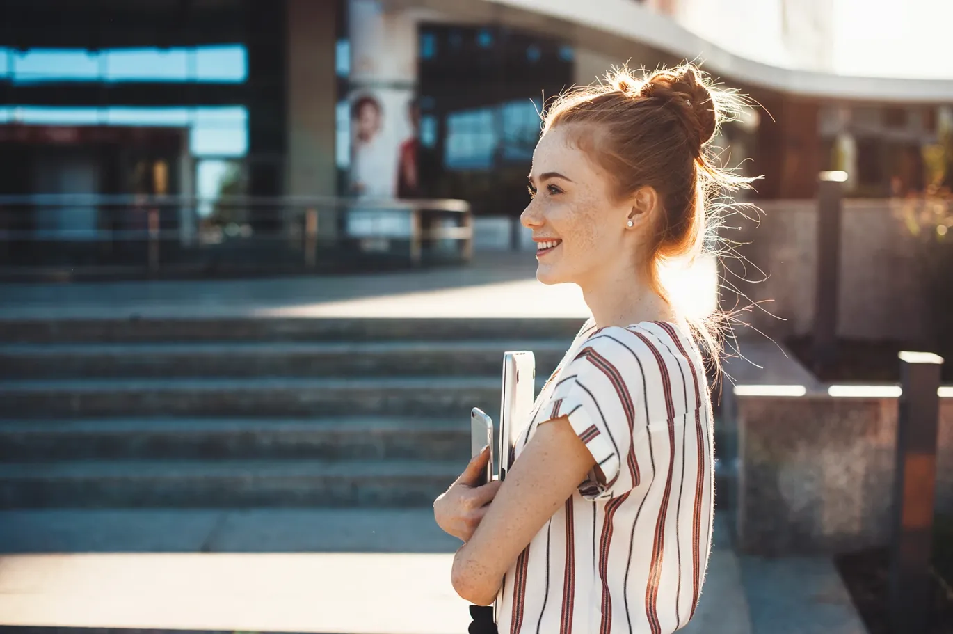 A girl standing with notes and mobile phone  near an IELTS test center