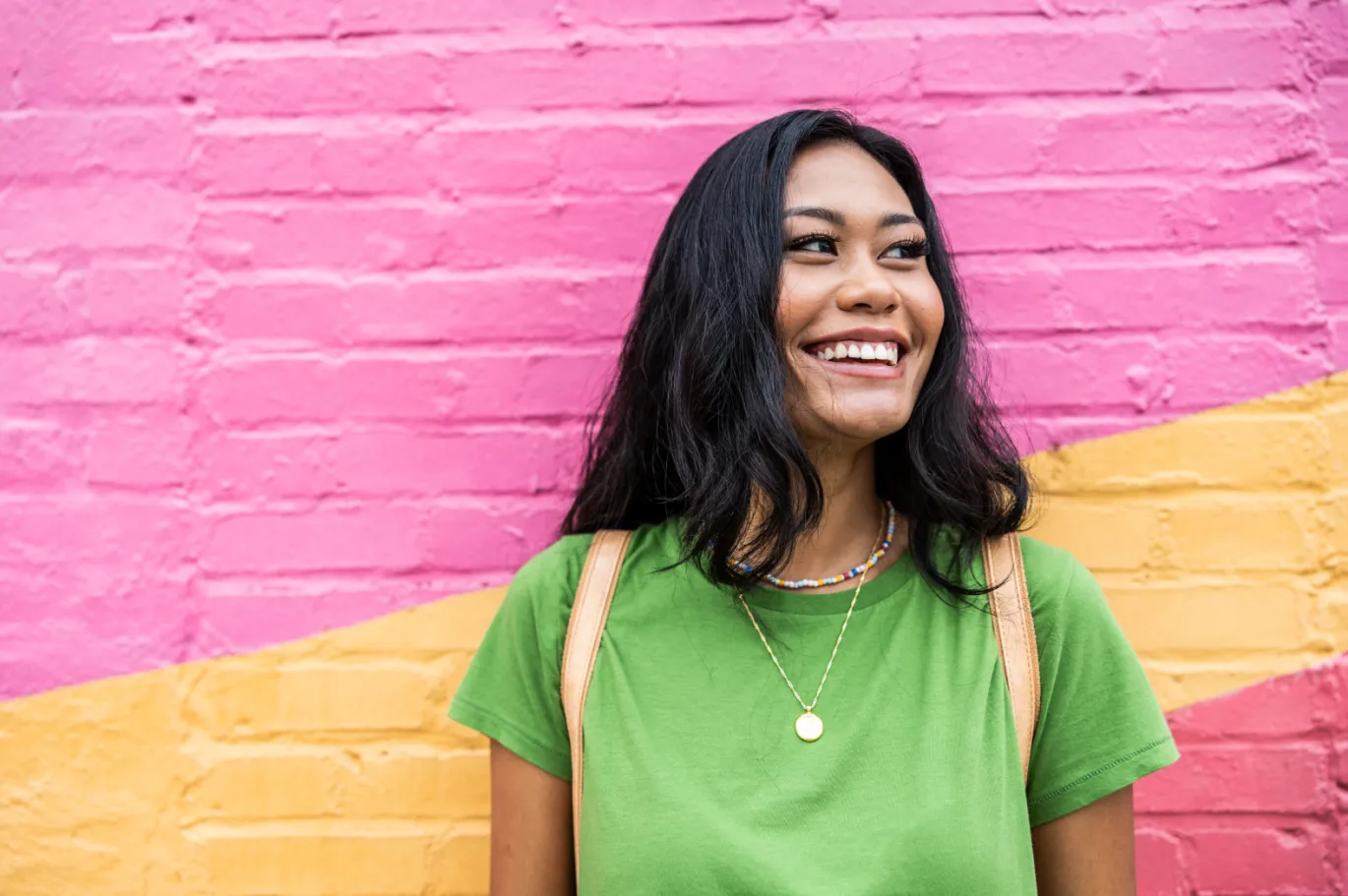 Smiling young woman standing in front of a colorful painted wall