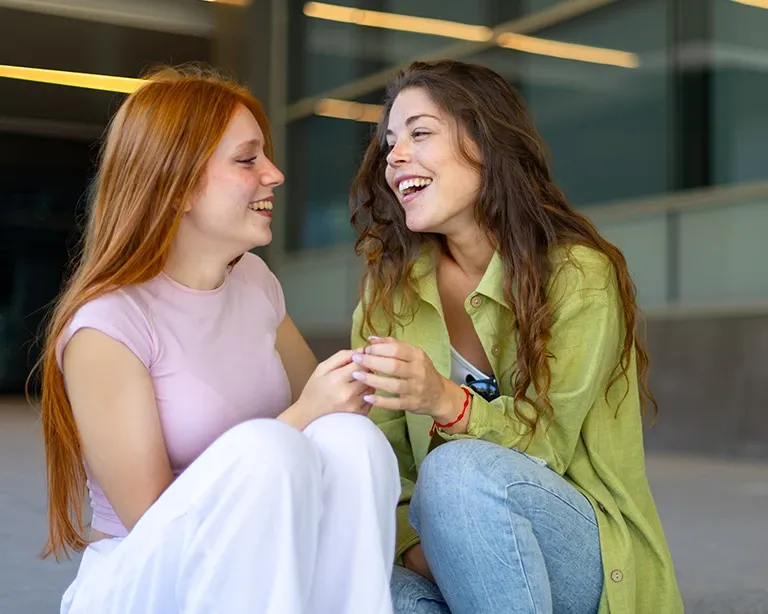 Two girls smiling at each other and discussing about IELTS exam